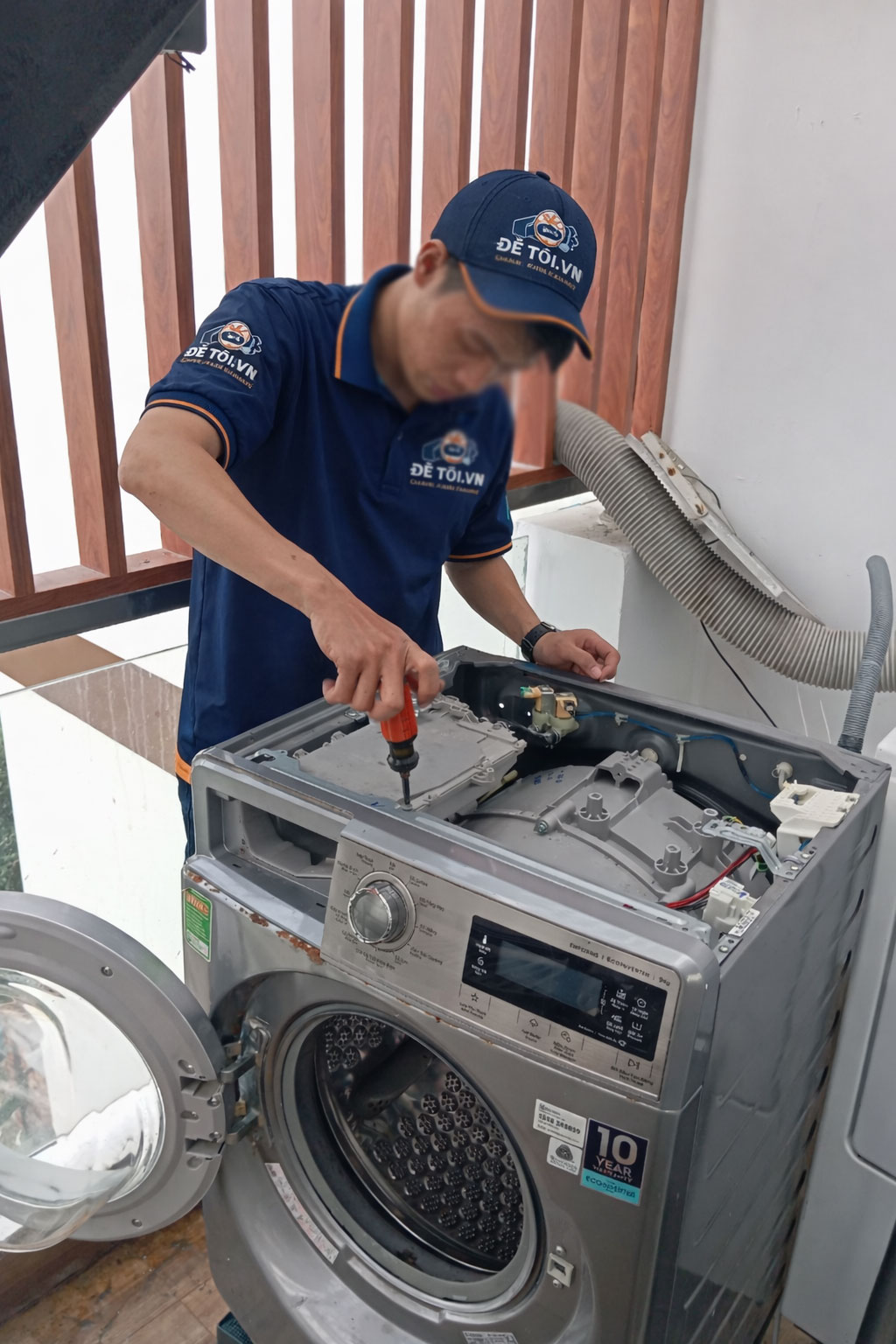 Thợ sửa máy giặt Để Tôi .VN đang mở nắp máy giặt để tiến hành kiểm tra và sửa chữa